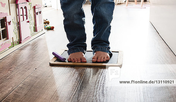 Low section of girl standing on slate with felt tip pen at home