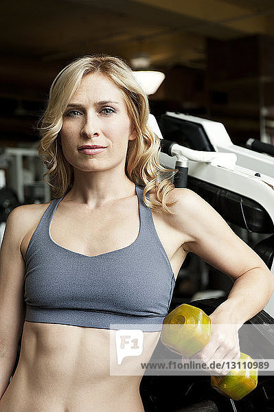 Porträt einer Frau beim Heben einer Hantel im Fitnessstudio
