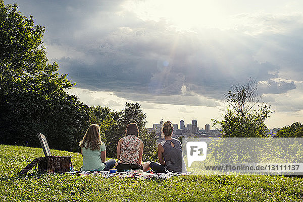 Rückansicht von Freundinnen  die an einem sonnigen Tag im Park entspannen