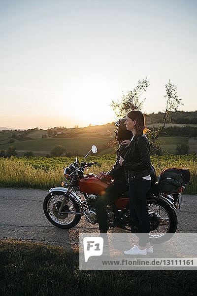 Junges Paar in voller Länge mit dem Motorrad auf der Landstraße