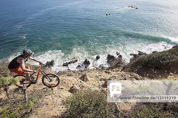 High angle view of athlete riding bicycle on rocky beach