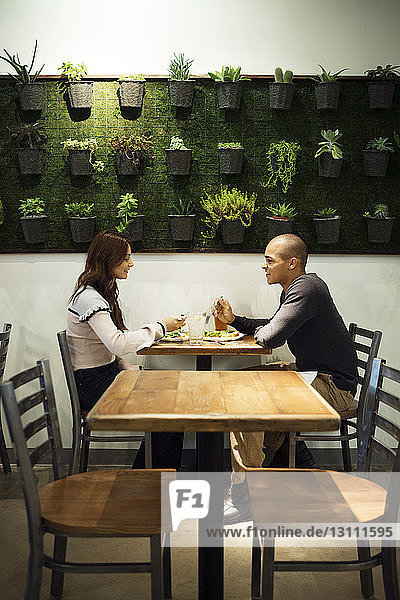 Side view of couple talking while having food in restaurant