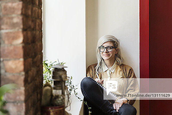 Porträt einer selbstbewussten jungen Geschäftsfrau  die in einem kreativen Büro sitzt