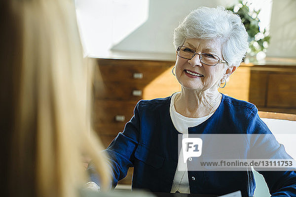 Lächelnde ältere Frau diskutiert mit amtierendem Finanzberater