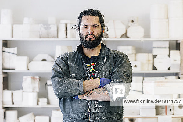 Portrait of confident craftsman with arms crossed standing at workshop