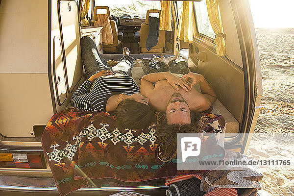 Romantisches junges Paar liegt während der Sommerferien am Strand des Bundesstaates San Onofre im Mini-Van