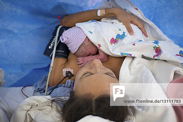 Father kissing newborn son sleeping in crib at hospital
