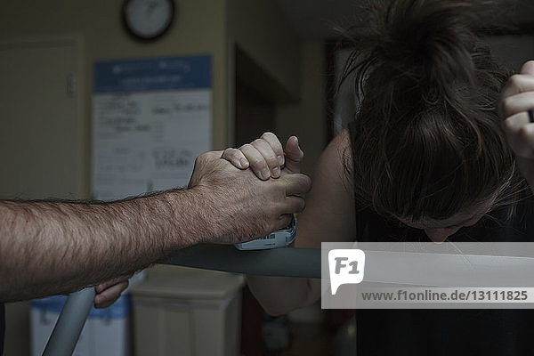Abgehackte Hand eines Mannes tröstet schmerzhafte schwangere Frau auf der Krankenhausstation