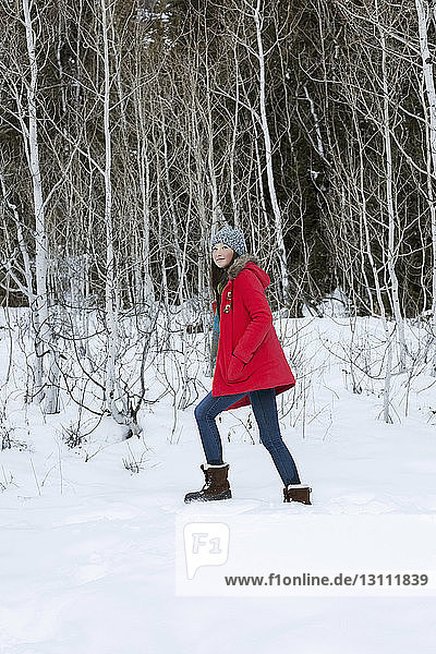 Girl walking on snowy field in forest