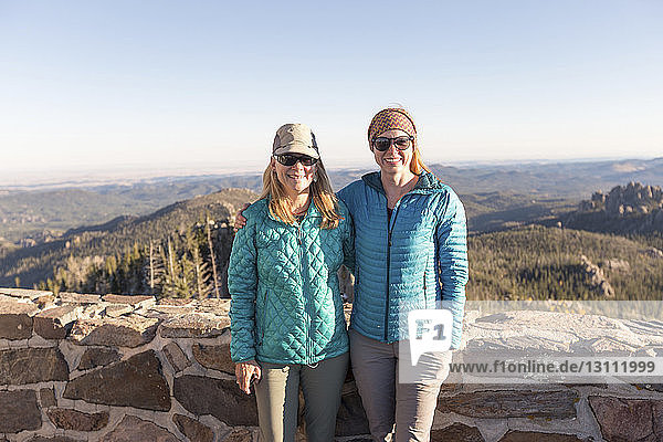 Portrait of mother and daughter standing against retaining wall at Custer State Park