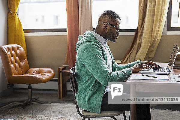 Side view of man using laptop at table