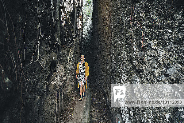 Frau geht inmitten von Felsformationen im Wald