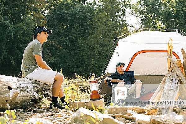Friends looking away while relaxing at campsite