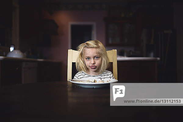 Portrait of cute girl making face while sitting at table