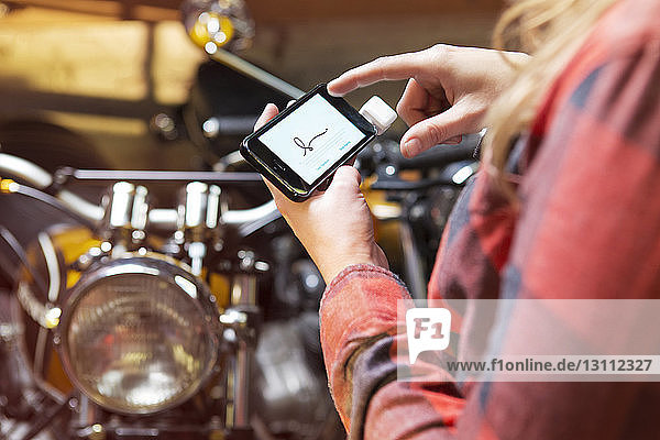 Cropped image of woman signing on smart phone at auto repair shop