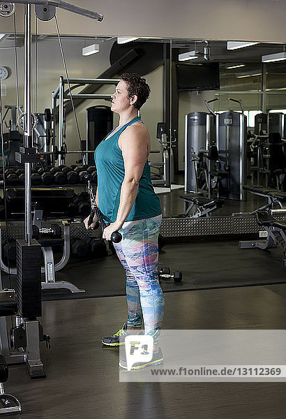Ganzflächige Seitenansicht einer im Fitnessstudio trainierenden Frau