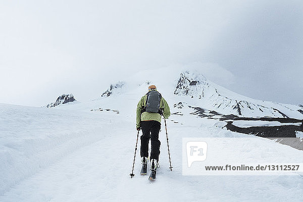 Rückansicht eines Mannes  der auf dem schneebedeckten Mount Hood wandert