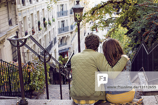 Rückansicht eines Paares  das auf Stufen in der Stadt sitzt