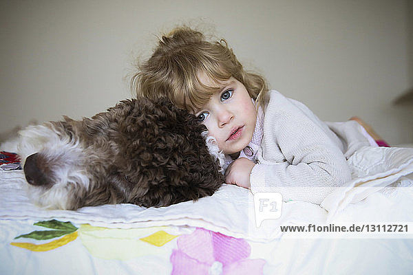 Portrait of girl relaxing with dog on bed at home