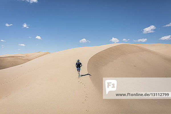 High angle view of woman walking on sand at Great Sand Dunes National Park during sunny day