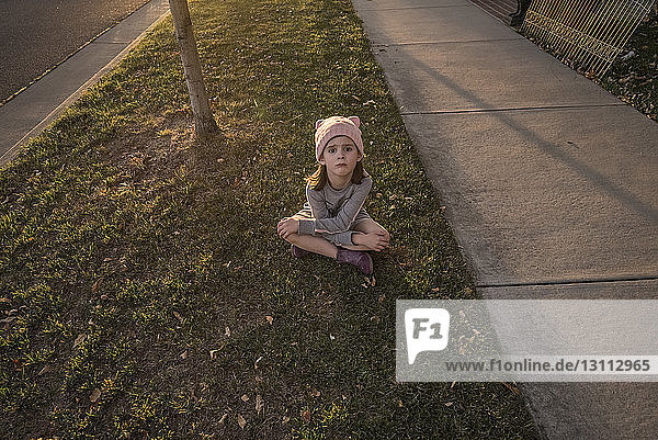 Hochwinkelporträt eines niedlichen Mädchens  das am Fußweg sitzt