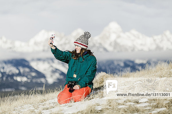 Wanderin  die im Winter mit einem Smartphone gegen die Berge geht