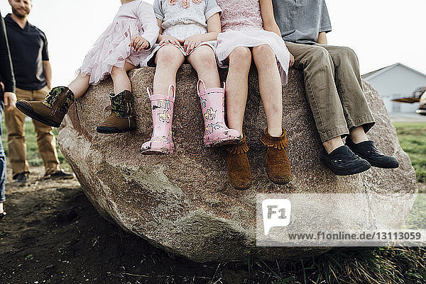 Low section of children sitting on rock