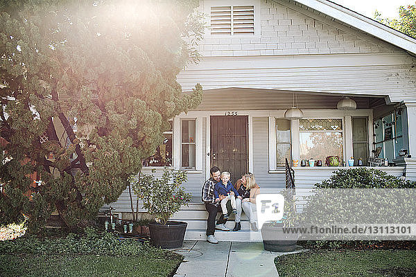 Happy parents with son sitting on steps of house