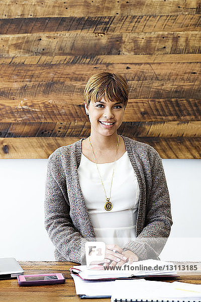 Porträt einer selbstbewussten Geschäftsfrau  die in einem kreativen Büro sitzt