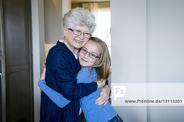Porträt einer Enkelin  die ihre Großmutter zu Hause umarmt