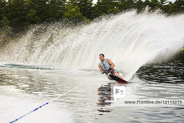 Man waterskiing in river at forest