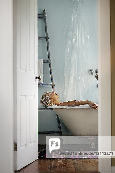Seitenansicht einer Frau  die sich zu Hause in der Badewanne entspannt