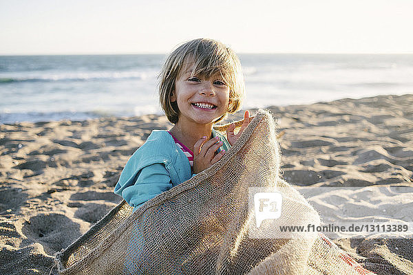 Porträt eines Mädchens  das in einem Sack am Strand sitzt