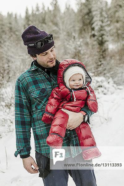 Vater trägt süße Tochter  während er im Winter im Wald steht