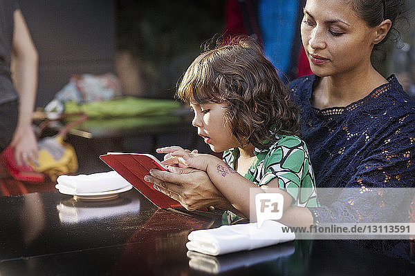Mutter und Tochter benutzen Tablet-Computer im Straßencafé