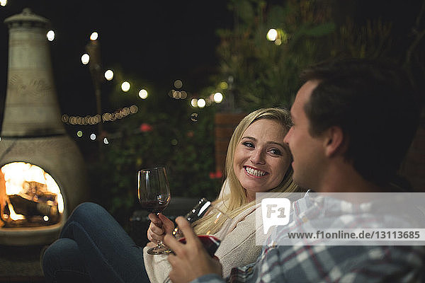 Paar mit Weingläsern sitzt auf dem Sofa auf der Terrasse