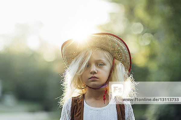 Portrait of girl wearing sun hat standing in park during sunny day