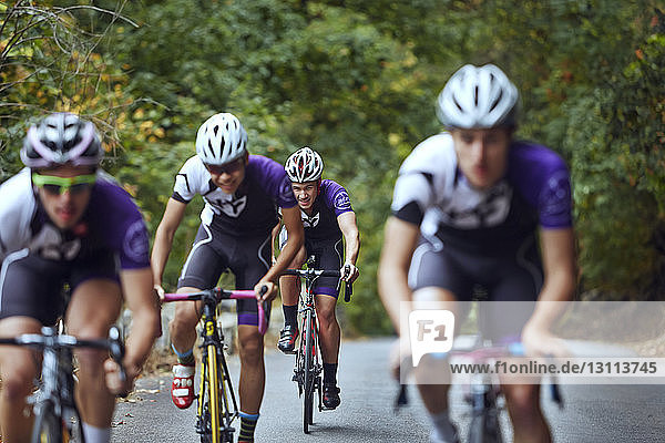 Male athletes friends riding bicycles on road