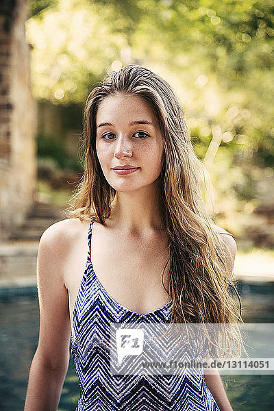 Portrait of confident teenage girl doing yoga at poolside