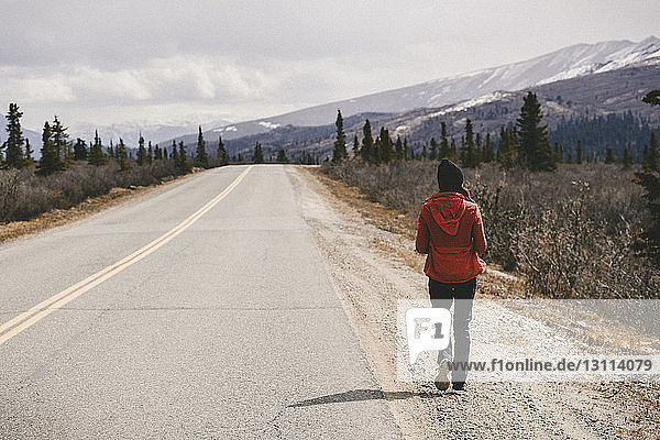 Rear view of woman walking by country road at Denali National Park