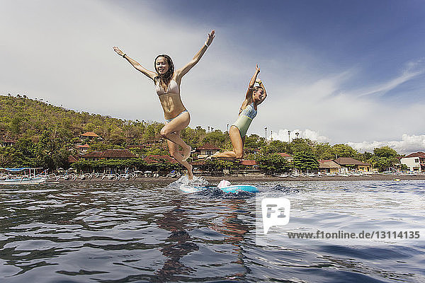 Tiefblick auf glückliche Frauen  die auf See gegen den Himmel springen
