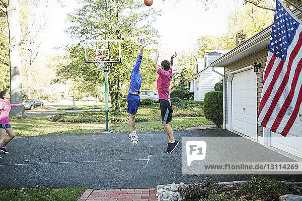 Älterer Mann spielt Basketball mit Enkel im Hinterhof