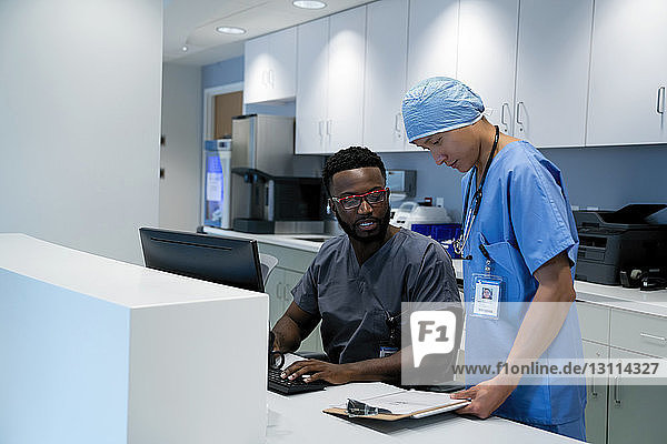 Doctor and surgeon reviewing medical chart on clipboard at hospital reception