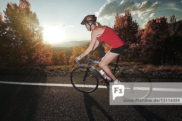 Female cyclist on road at sunset