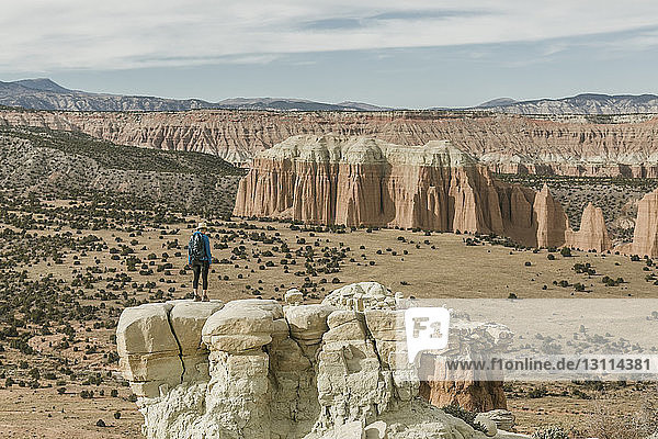 Full length of female hiker standing on rock formation at desert