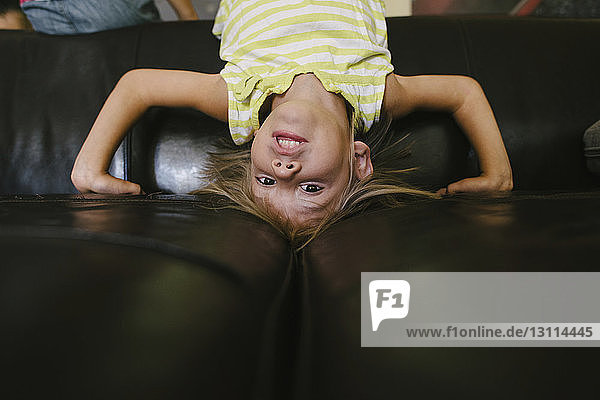 Portrait eines Mädchens auf dem Kopf auf dem heimischen Sofa