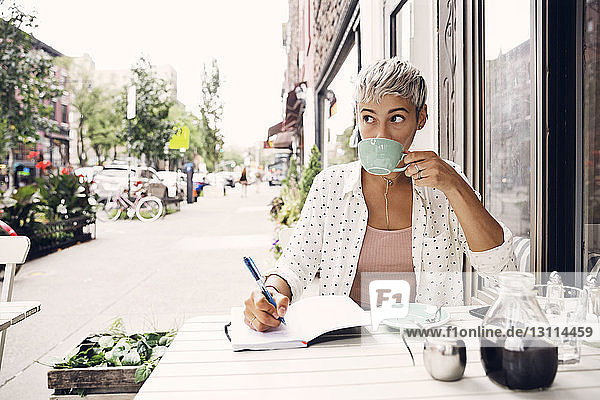 Woman drinking coffee at sidewalk cafe