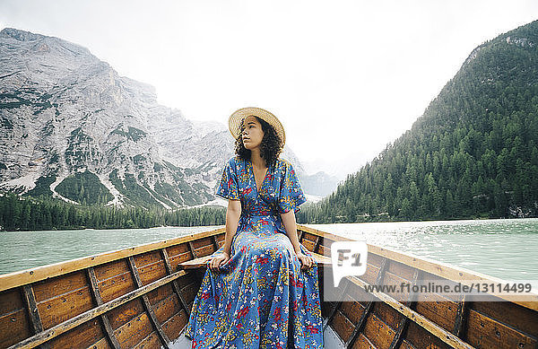 Frau schaut weg  während sie im Ruderboot über dem See gegen Berge sitzt