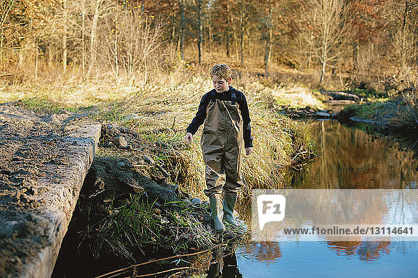Junge steht am Seeufer im Wald