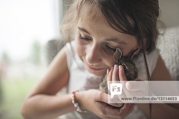 Close-up of girl holding bunny while sitting at home